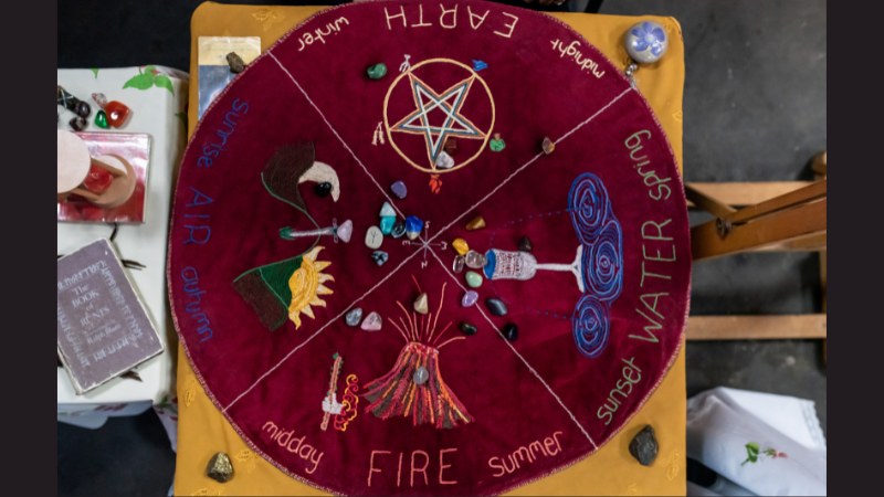 Hand-embroidered Southern Hemisphere medicine wheel cloth on a table at a market, with runes cast on top.